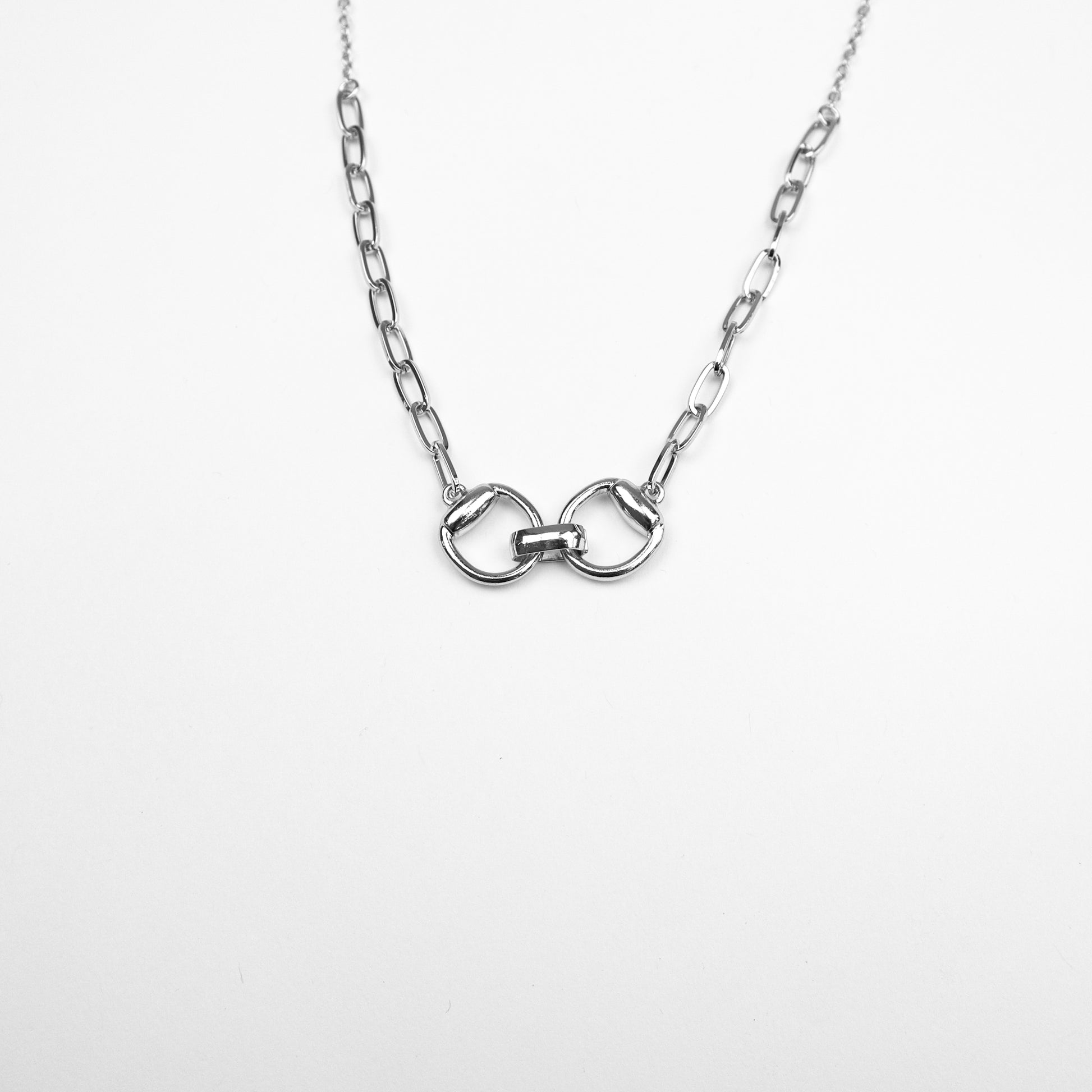 A sleek silver-tone necklace with an interlocking belt buckle pendant, perfect for a modern and minimalist aesthetic.

