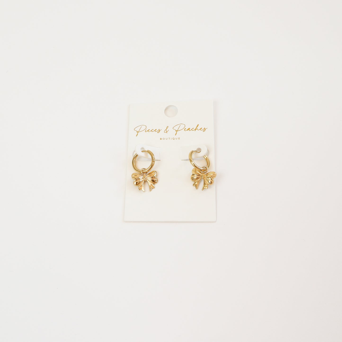 Gold huggie hoop earrings with delicate bow-shaped charms