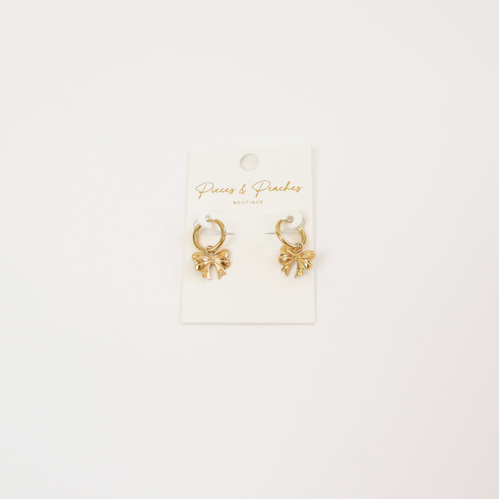 Gold huggie hoop earrings with delicate bow-shaped charms