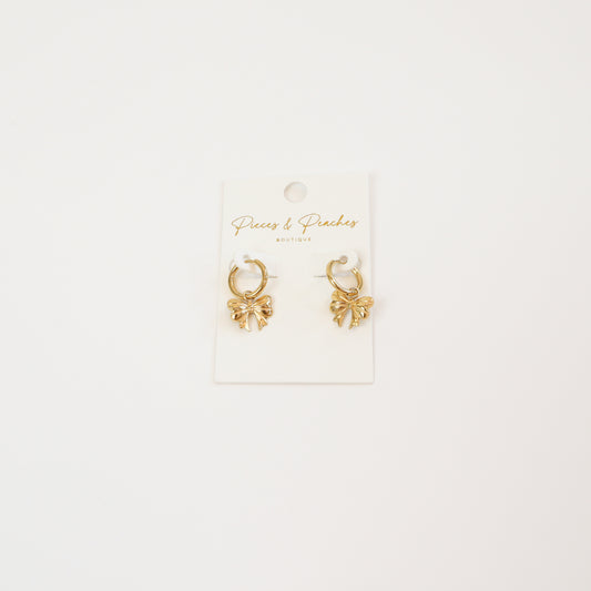 Gold huggie hoop earrings with delicate bow-shaped charms