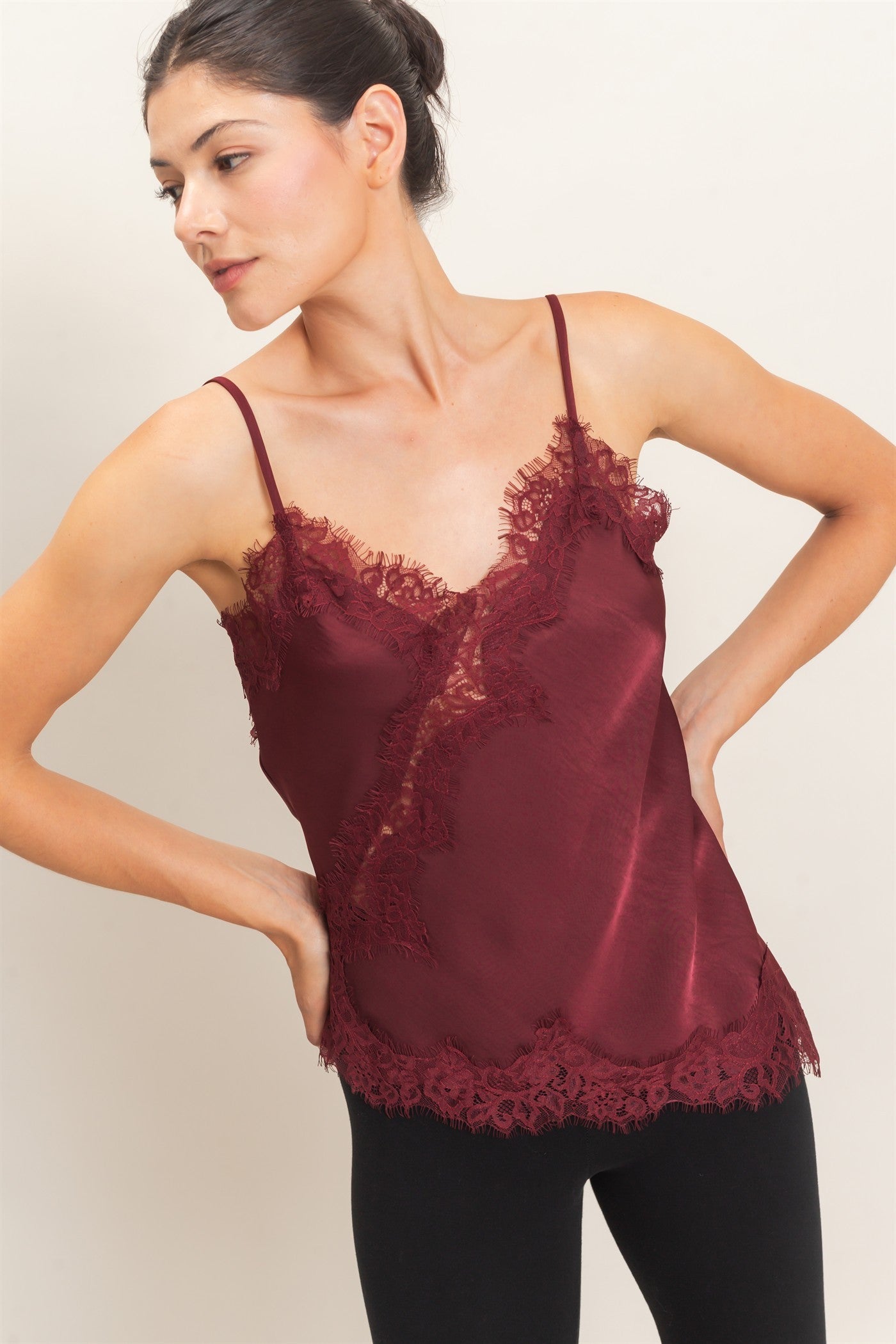 A delicate asymmetrical lace camisole with adjustable straps and feminine lace trim, designed to elevate your favorite layered looks.