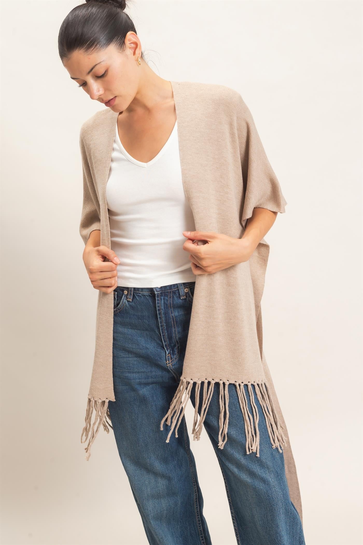 A chic open-front kimono sweater with wide sleeves, a self-tie waist, and statement fringe trim that adds effortless movement to any outfit.