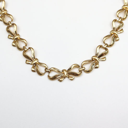 Gold-tone bow chain necklace with intricate link design
