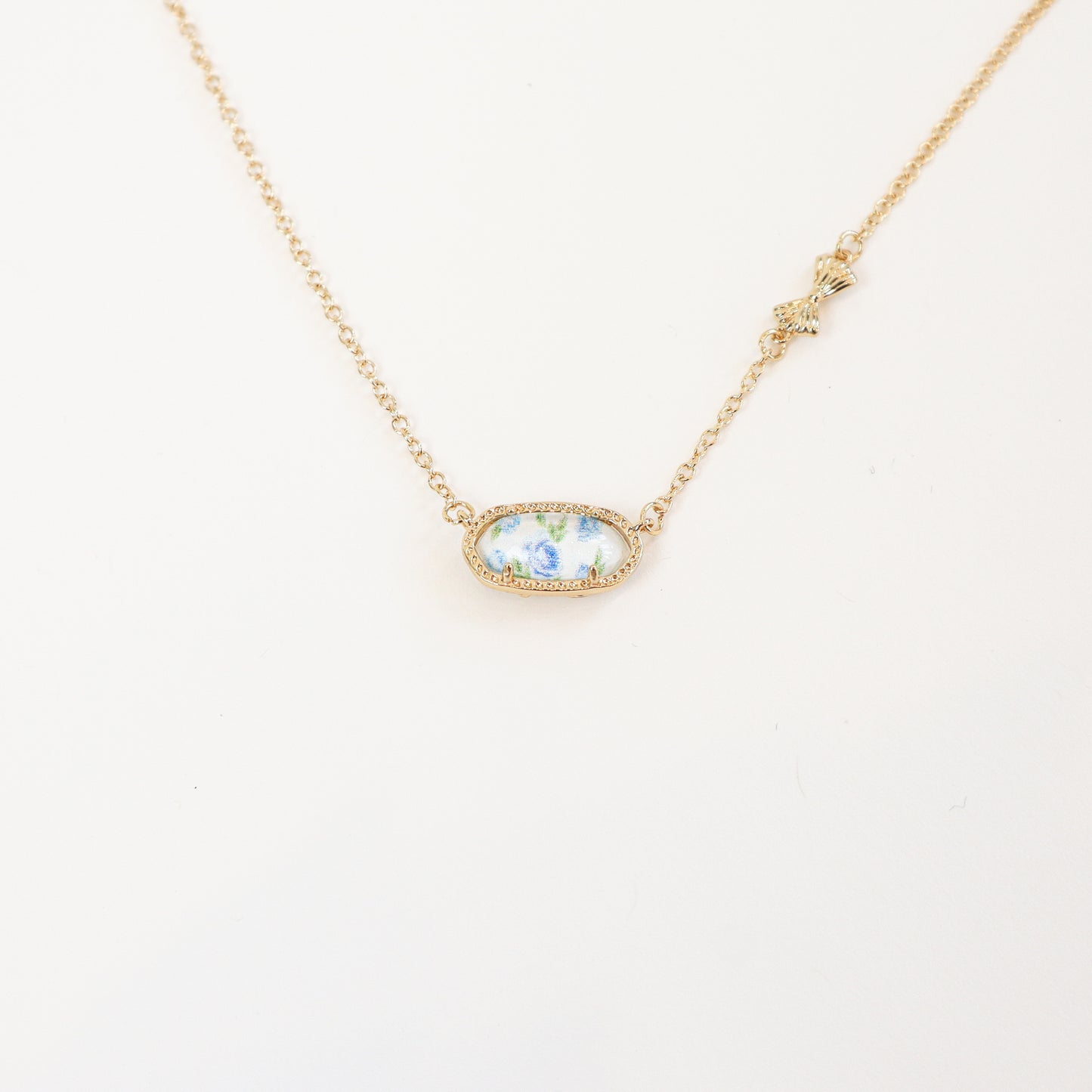 18K gold-plated reversible pendant necklace with a blue floral design on one side, displayed on a delicate gold chain