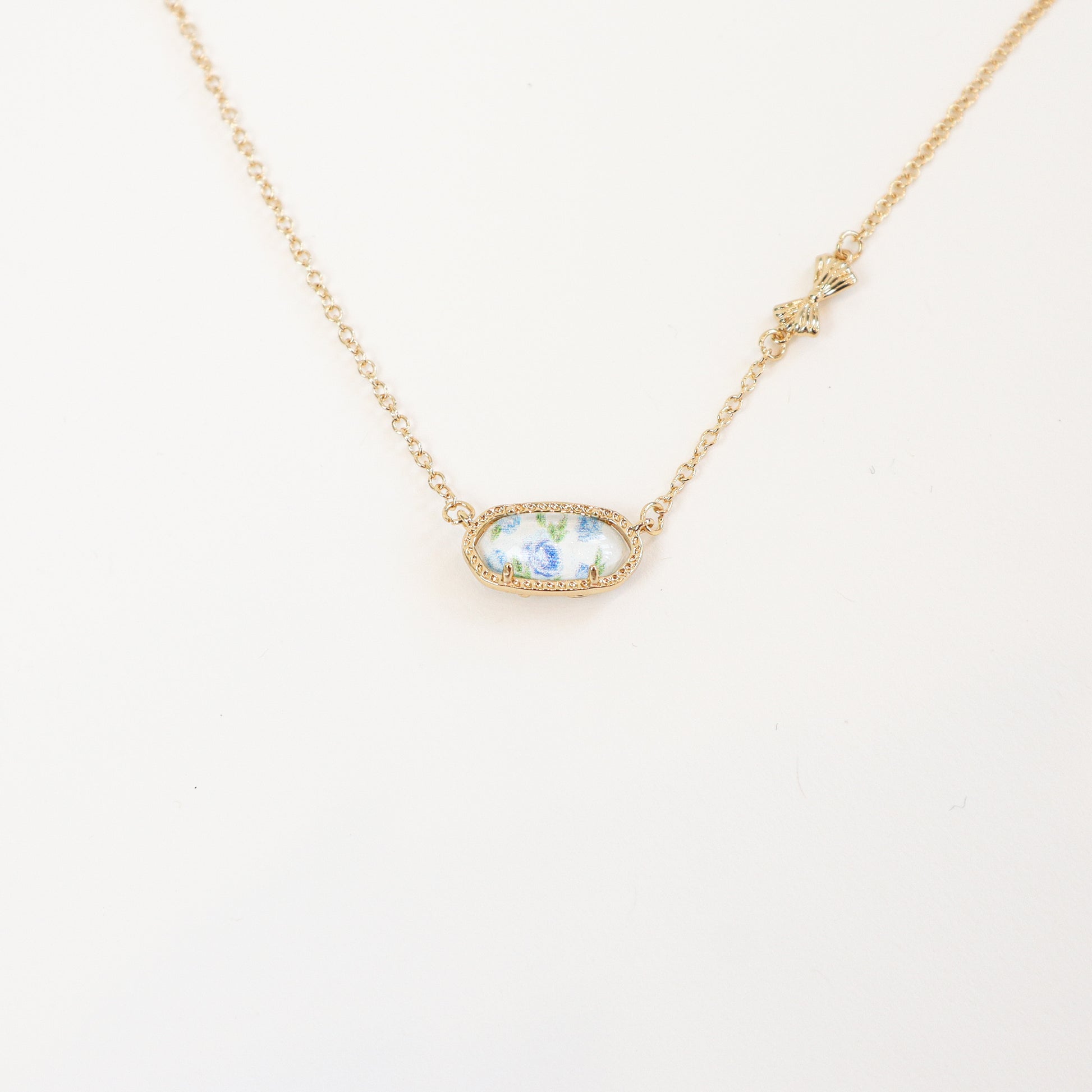 18K gold-plated reversible pendant necklace with a blue floral design on one side, displayed on a delicate gold chain