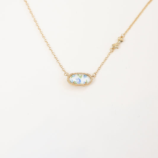 18K gold-plated reversible pendant necklace with a blue floral design on one side, displayed on a delicate gold chain