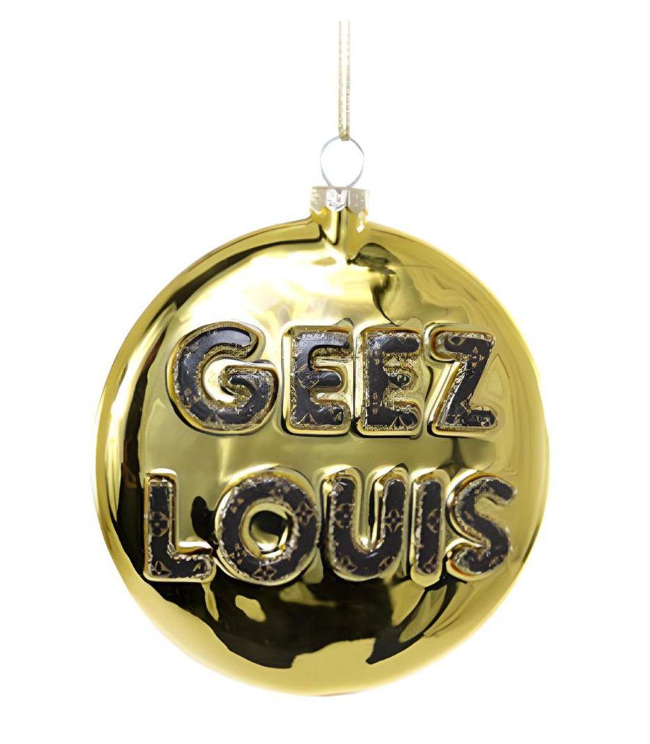 Gold Christmas ornament with bold black “Geez Louis” lettering, hanging by a gold ribbon — a fun and glamorous holiday decoration.