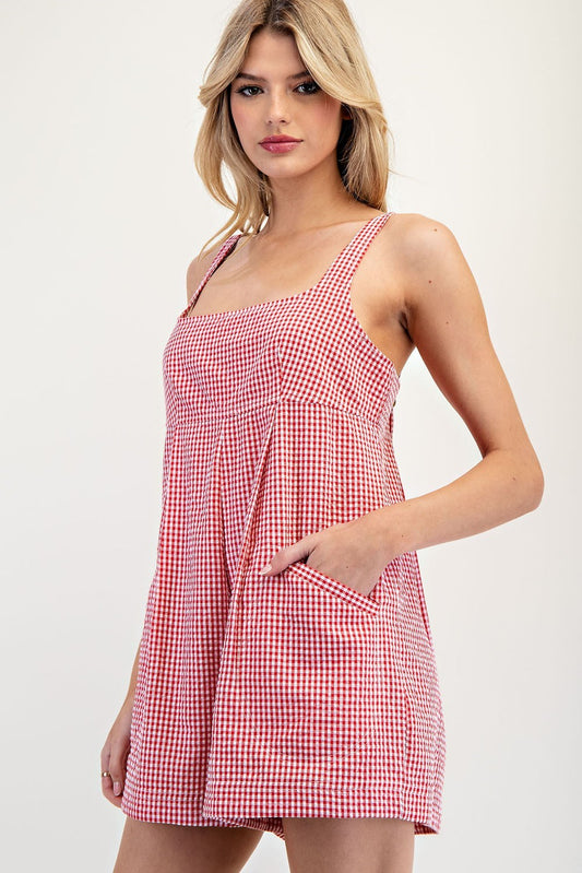 Red and white gingham sleeveless romper featuring an A-line silhouette, adjustable straps, and side pockets for a charming and versatile summer look.