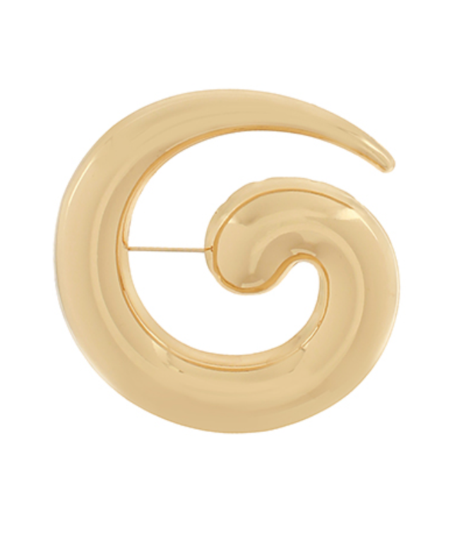 A large, highly polished gold-toned brooch in a distinct "G" or spiral swirl shape, with a subtle texture or ridge suggesting its form, and a discreet pin mechanism on the back.