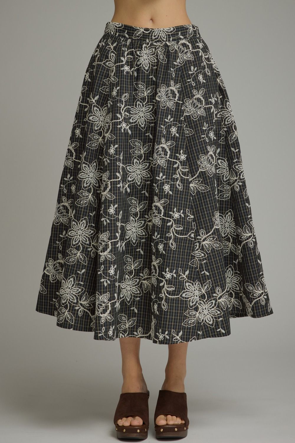 A timeless plaid midi skirt featuring delicate floral embroidery and a flattering silhouette for effortless everyday elegance.
