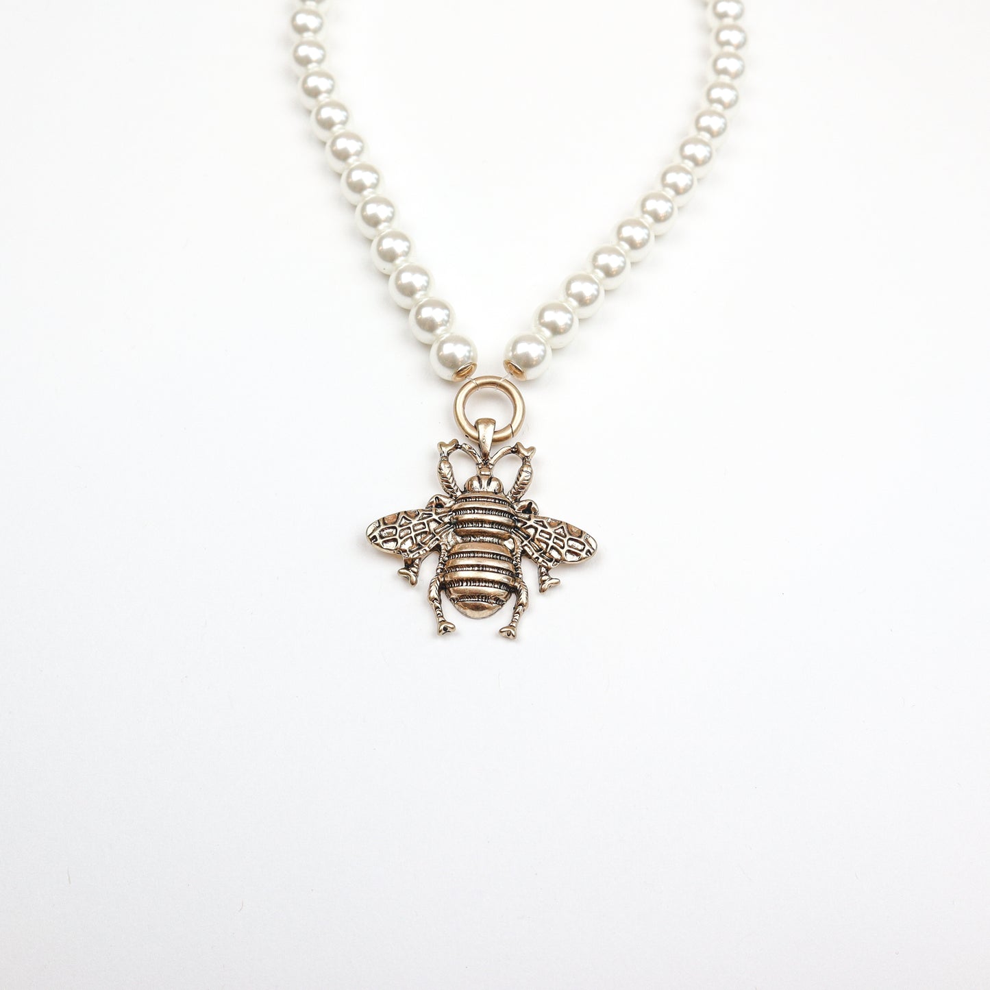 A stunning pearl necklace featuring an intricately designed bee pendant, blending elegance with nature-inspired charm.
