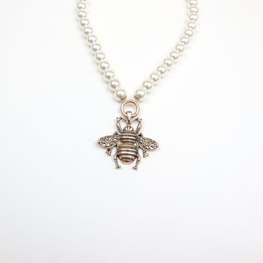A stunning pearl necklace featuring an intricately designed bee pendant, blending elegance with nature-inspired charm.
