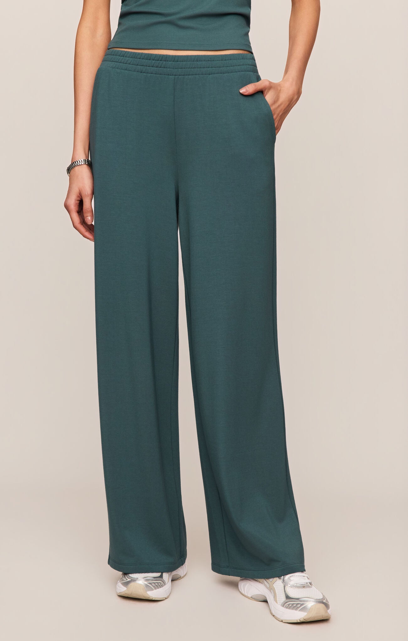 Teal wide-leg pants worn by a person on a beige background