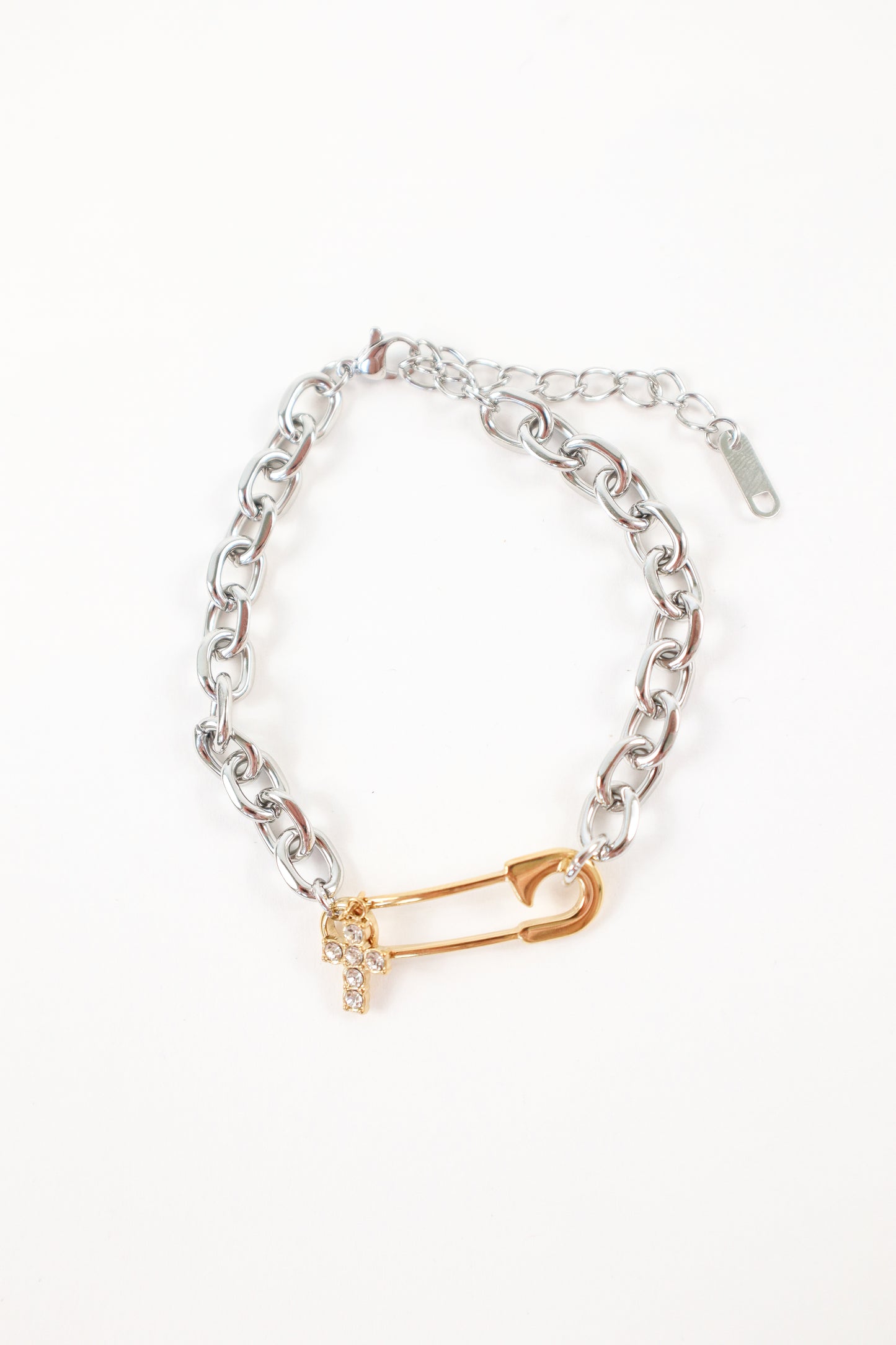 Mixed metal safety pin bracelet featuring silver chain and gold cross charm detail