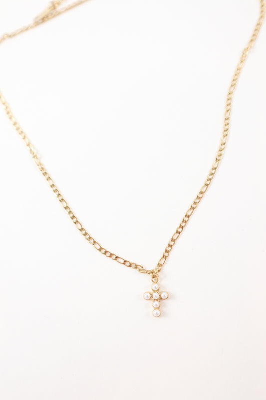 Delicate gold chain necklace featuring a small pearl cross pendant, styled as a minimalist faith-inspired jewelry piece.