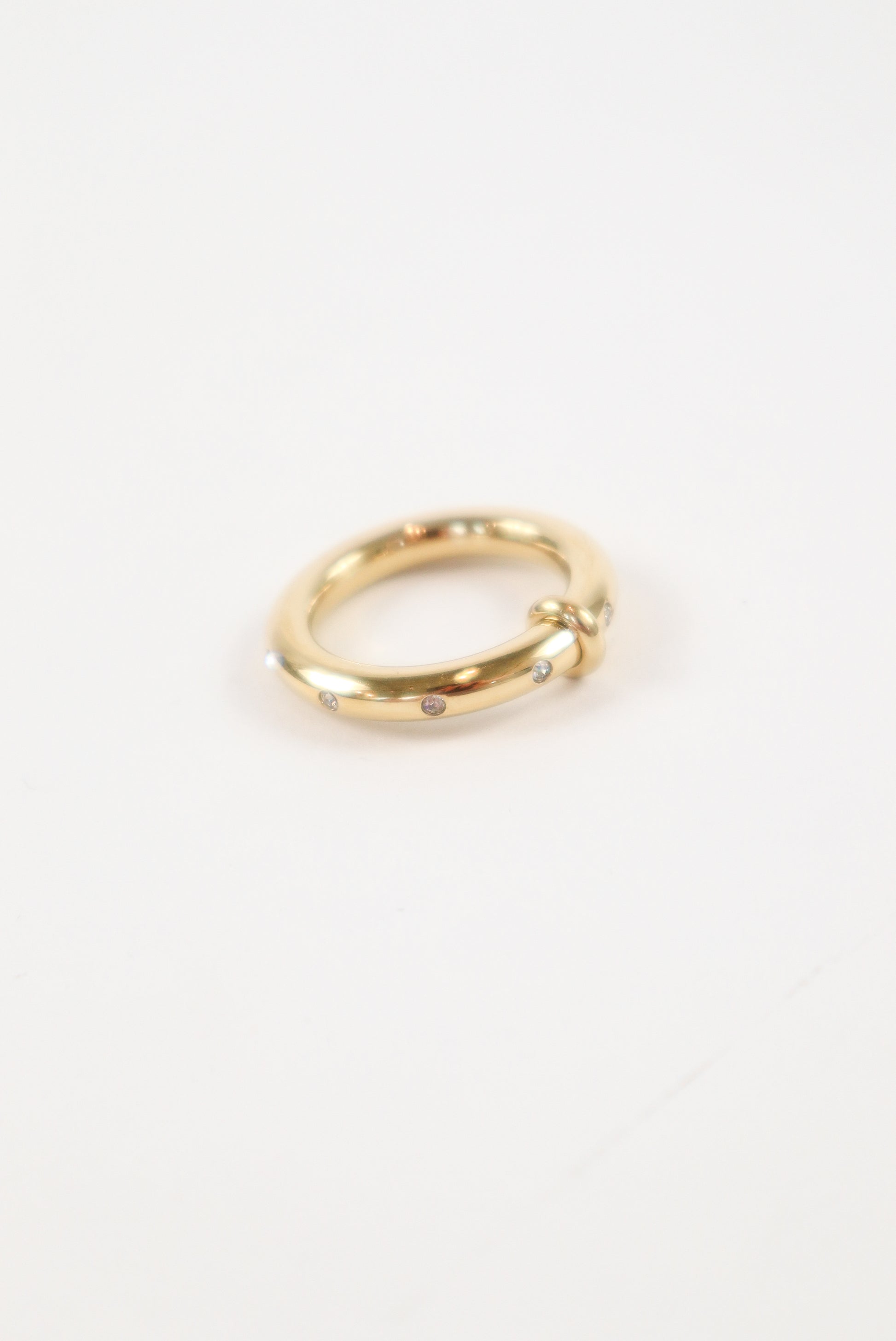 14K yellow gold knot ring with small round diamond accents on a polished minimalist band