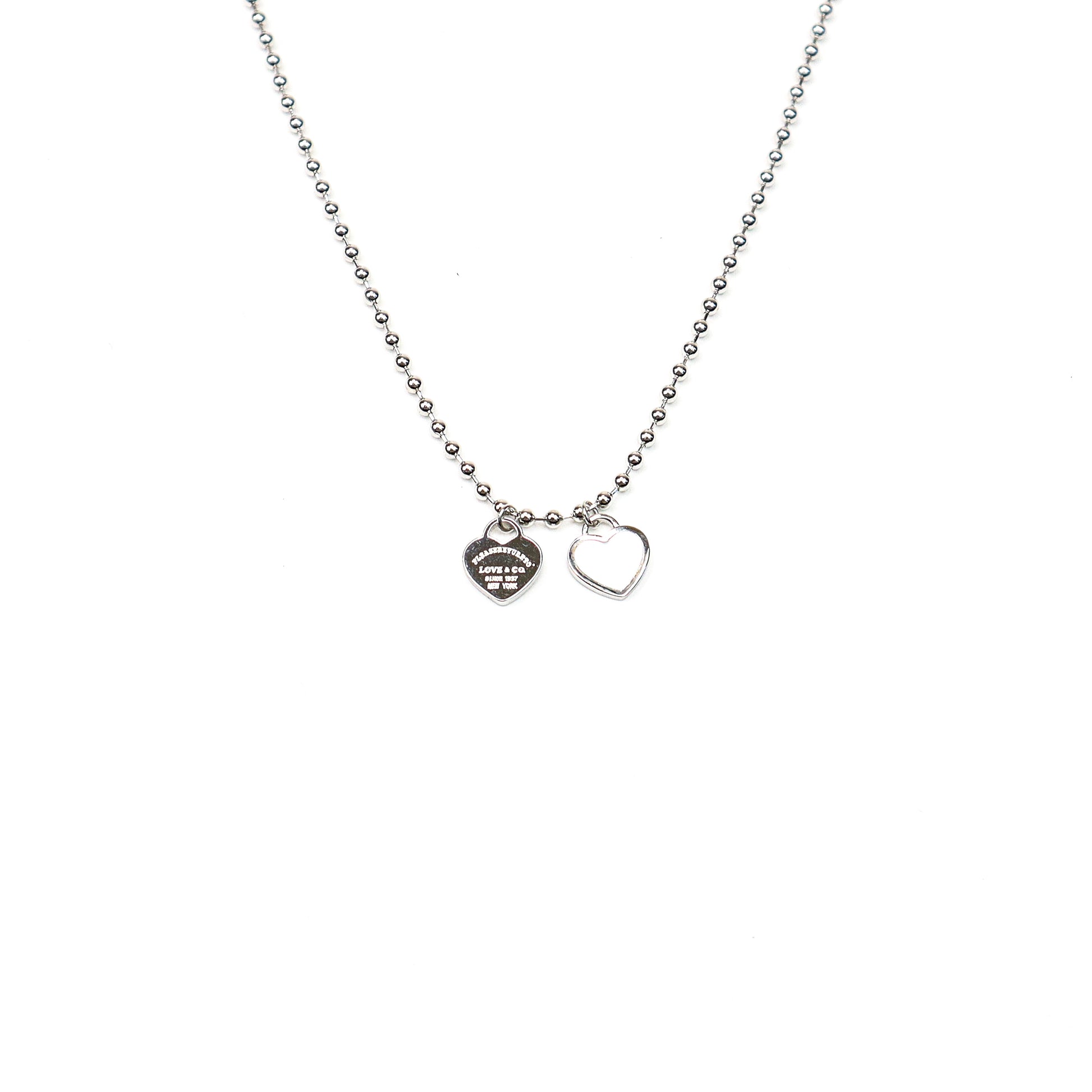 Silver beaded chain necklace with two heart charms, featuring a polished finish and engraved detailing for a timeless, elegant look