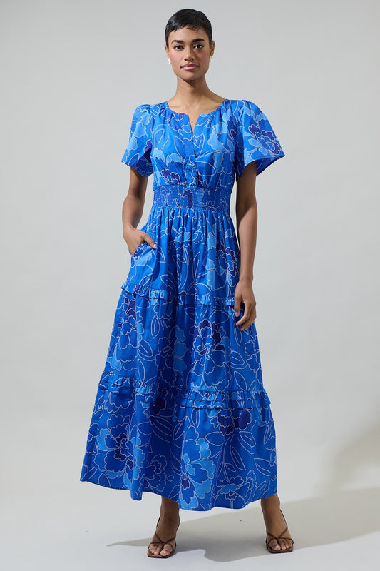 Blue floral maxi dress with flutter sleeves, a smocked waist, and tiered ruffle details, perfect for elegant summer styling.