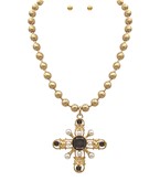 Gold-tone bead necklace with a large cross pendant featuring dark stones and pearl-like accents, shown with matching stud earrings on a white background.