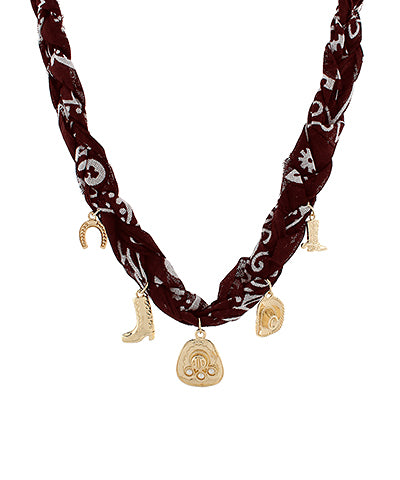 Close-up of a Western Bandana Charm Necklace featuring a burgundy braided fabric with five gold-tone Western-themed charms, including cowboy boots and a horseshoe, perfect for boho and cowgirl-inspired looks.