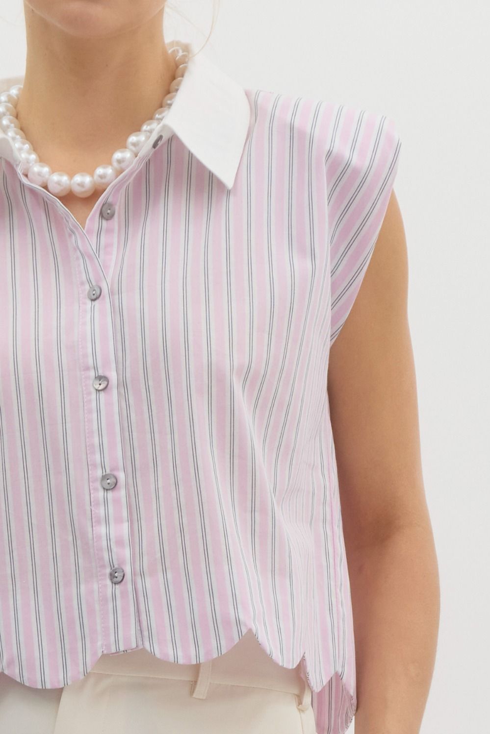 Pinstriped structured shoulder sleeveless top featuring scalloped hem. Classic collared front butto closure. Unlined. Woven. Non-sheer. Lightweight.
