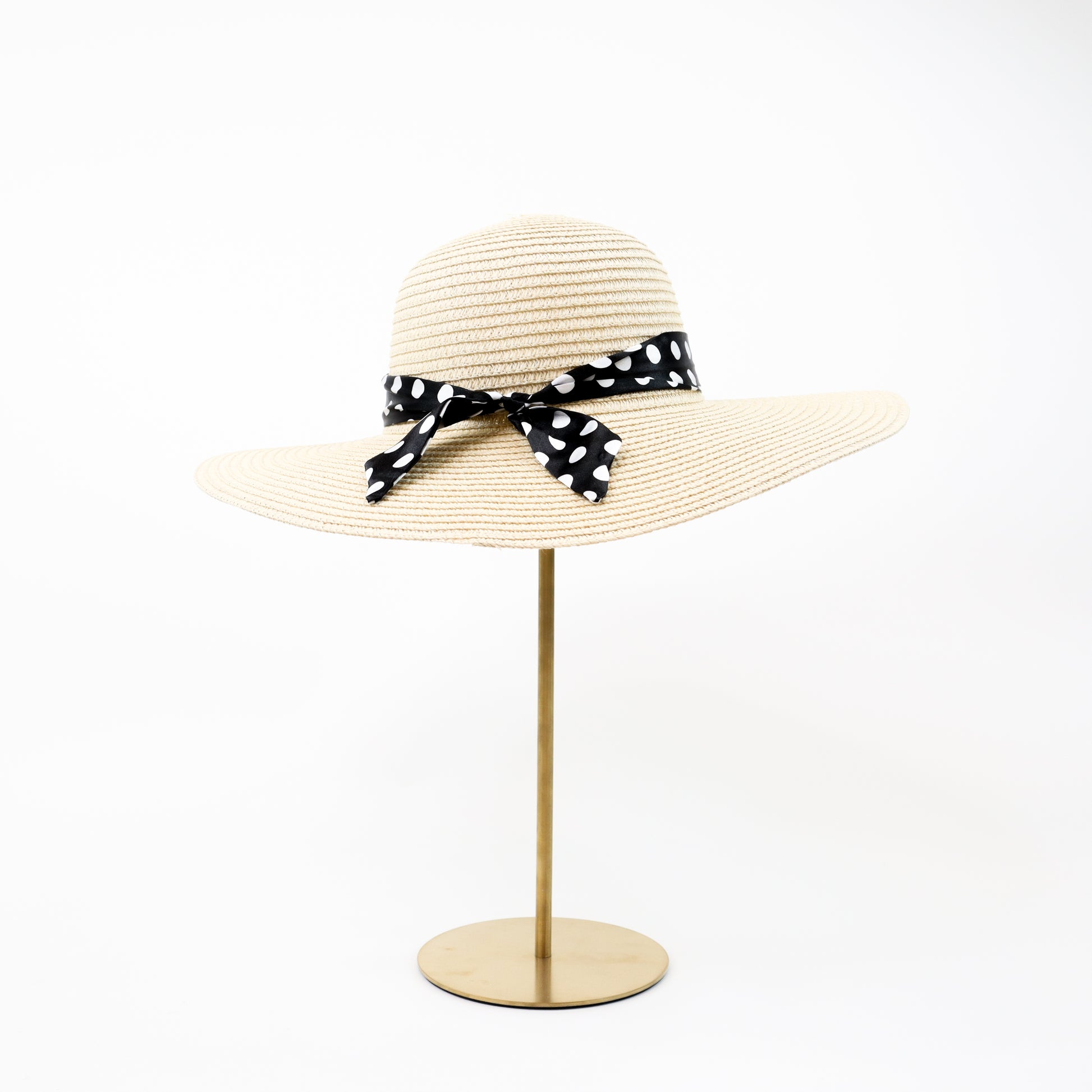  A timeless natural straw sun hat with a black and white polka dot ribbon bow, ideal for sun protection with a fashionable twist.