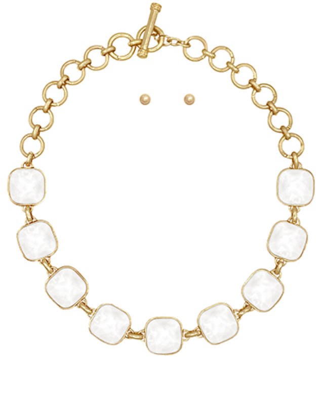 A gold-toned necklace featuring a series of evenly spaced, large, rounded square white cabochon stones, linked by smaller gold rings, and fastened with a toggle clasp.
