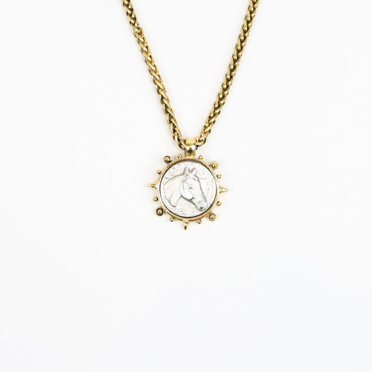  A 22K gold-plated equestrian-inspired necklace featuring a detailed stallion medallion pendant encased in a sunburst-style frame, suspended from a bold gold chain.