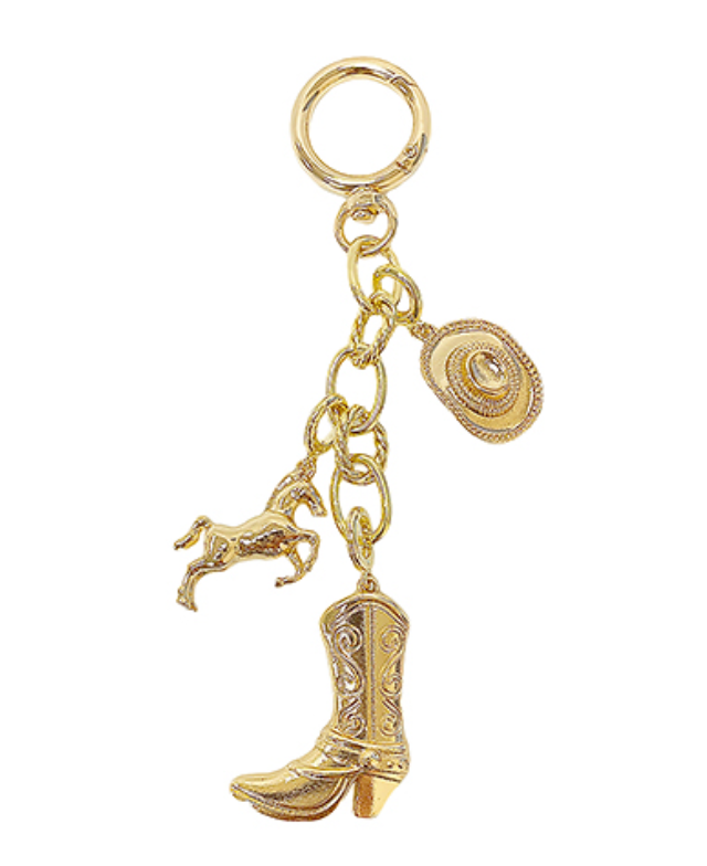 A gold-toned bag charm or keychain featuring a lobster clasp at the top, from which suspends a chain holding three western-themed charms: a small, rearing horse, a cowboy hat, and a detailed cowboy boot.