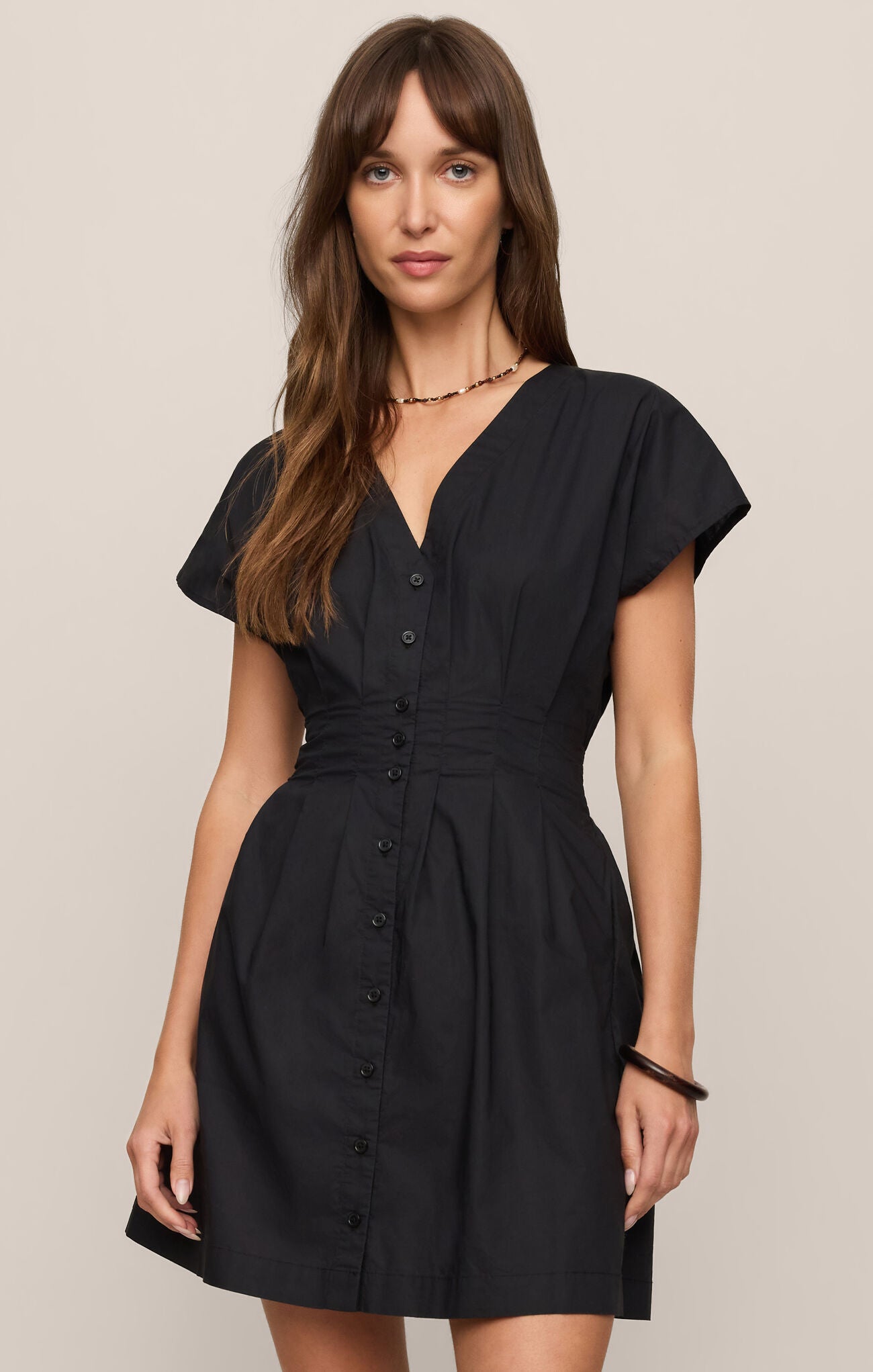 cotton poplin mini dress featuring a flattering V-neckline, short sleeves, and button-front design.
