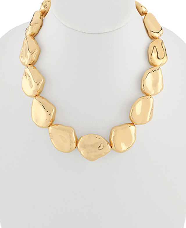 A short, gold-toned statement necklace composed of large, irregular, organic-shaped links or beads with a high-shine, hammered or sculpted finish. The shapes are somewhat flat and varied, creating a modern, artistic look.