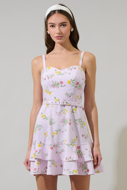 A pastel floral mini dress featuring a sweetheart neckline, adjustable straps, a cinched waist with a matching belt, and a tiered ruffle hem, creating a feminine and elegant look.