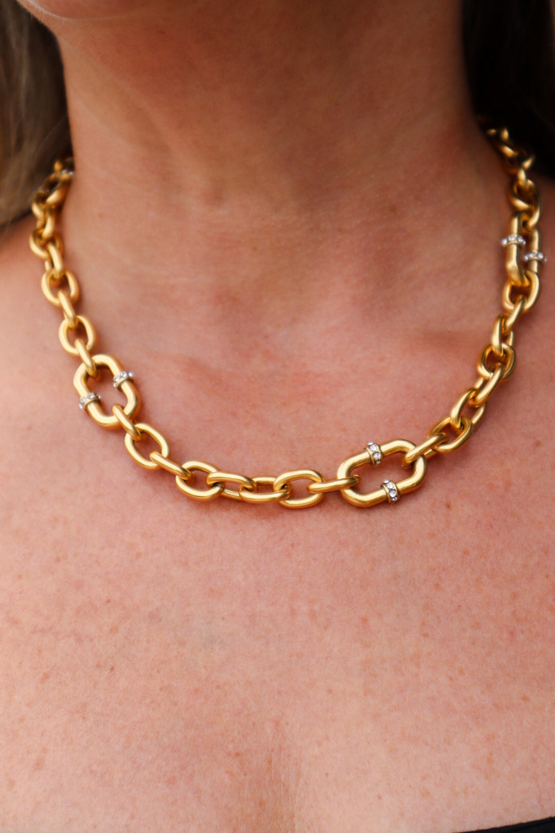 A 22K gold-plated chain necklace featuring bold interlocking links with crystal-accented connectors, exuding luxury and elegance.
