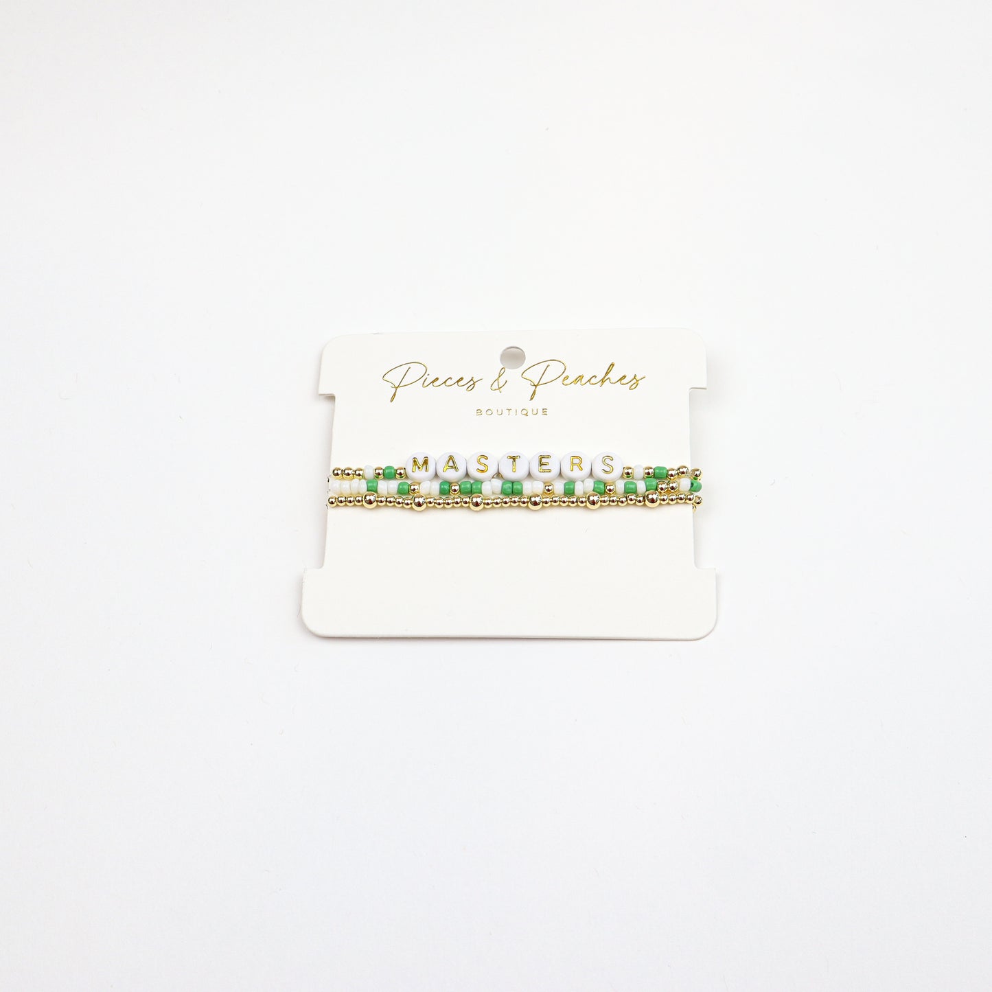 Masters Bracelet Stack featuring green, white, and gold beads with letter beads spelling “MASTERS.”