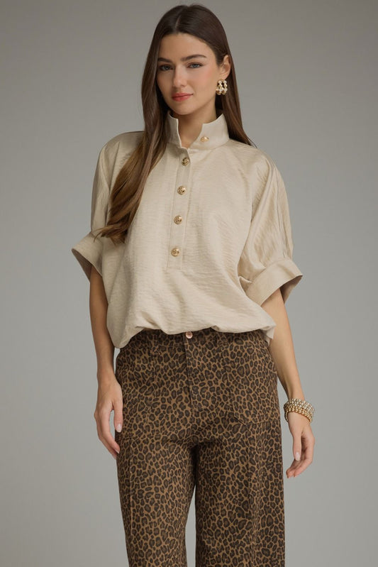 A polished solid short sleeve top featuring a sophisticated stand collar, partial button front, and softly structured cuffed sleeves.

