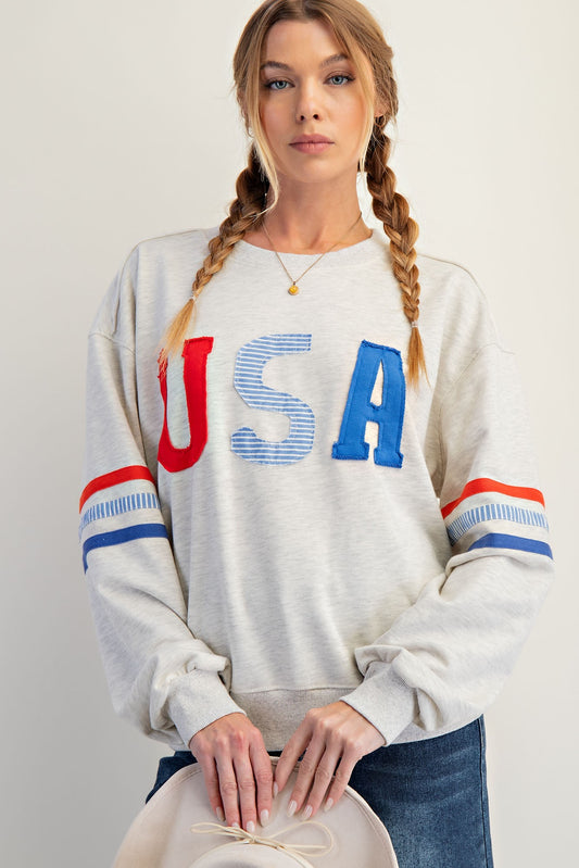 The Claribel Pullover features bold USA patch lettering, colorblock stripes, and a comfy relaxed fit—perfect for effortless patriotic style.