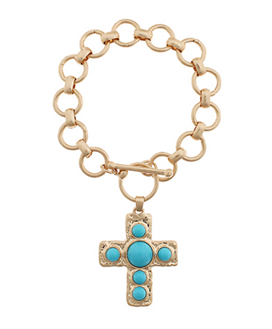 A gold-toned toggle bracelet with large, circular links, featuring a textured gold cross pendant embellished with five round, smooth turquoise cabochon stones.
