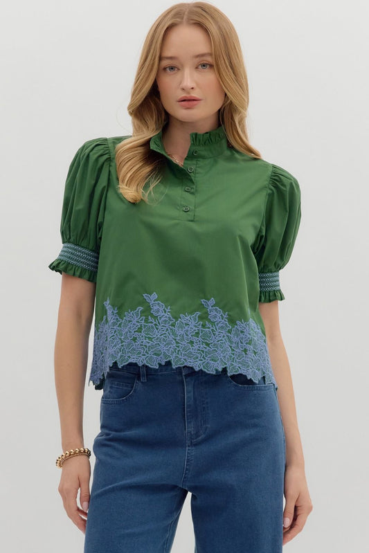 The Greta Embroidered Ruffle Blouse features a romantic ruffle collar, smocked cuffs, and detailed border embroidery for an elevated everyday look.