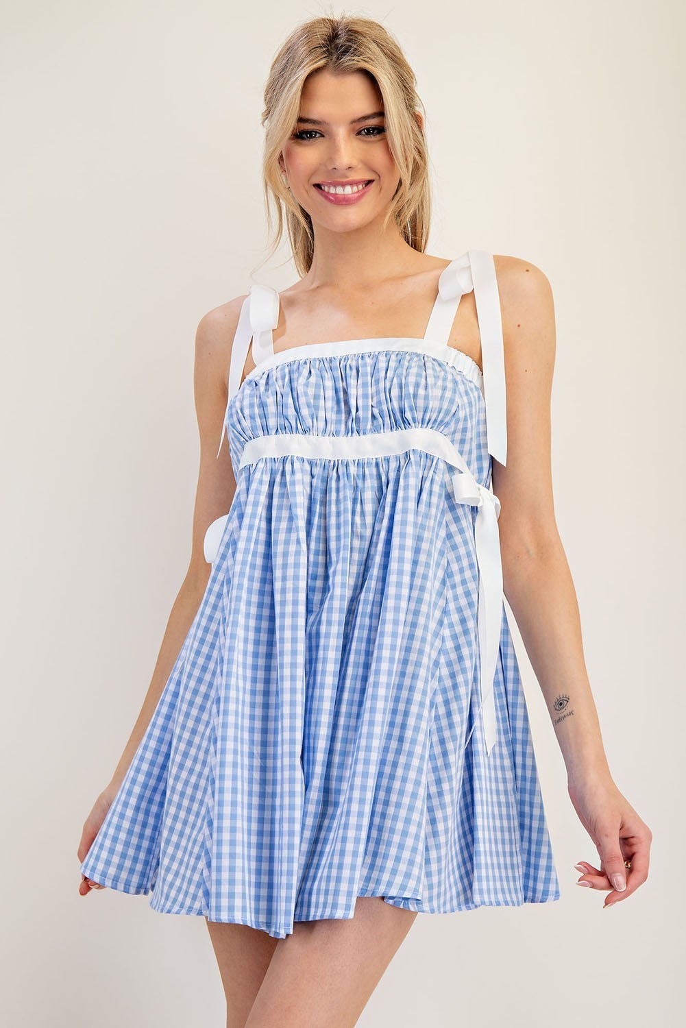 The Lilia Dress is a feminine gingham mini with adjustable bow-tie straps, a ruched bodice, and a flared skirt—perfect for summer outings, brunches, or vacations.

