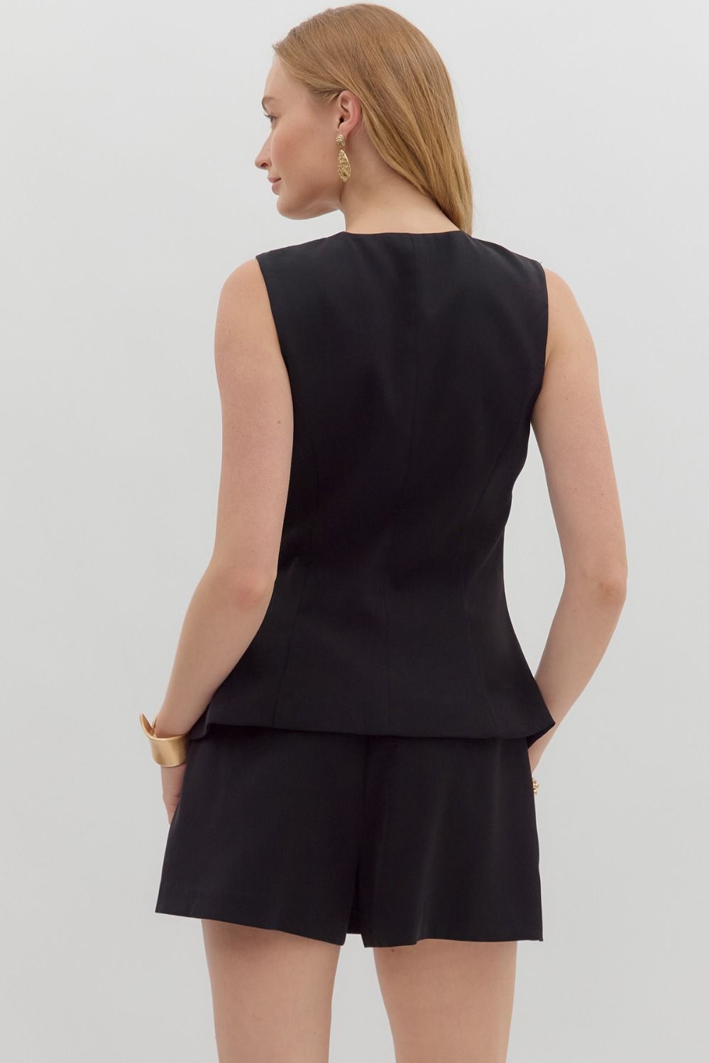 The Romina Romper features a sleek sleeveless design with gold button accents, a concealed zipper, and lightweight lining—your one-and-done outfit for chic days or nights.