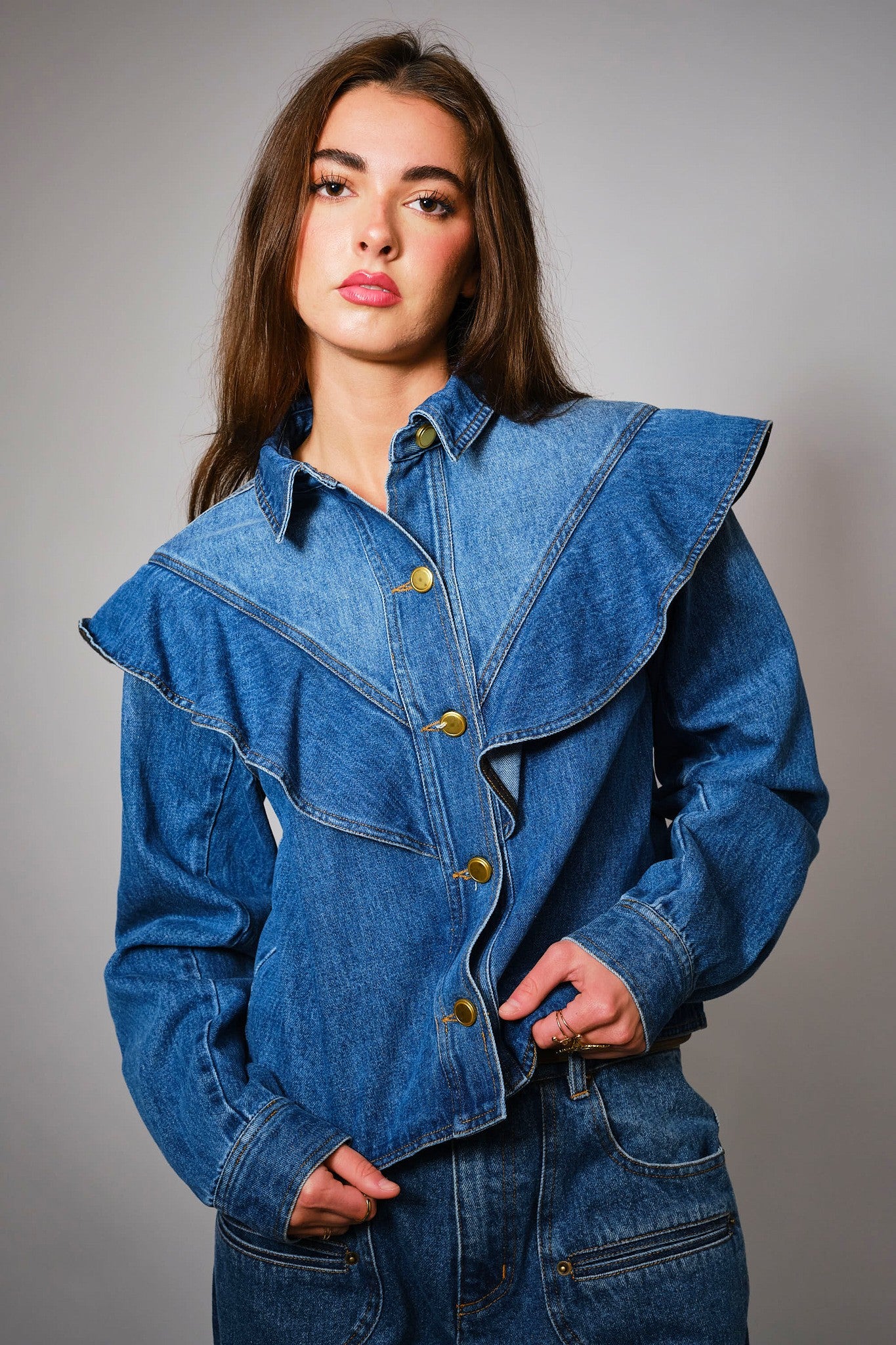 The Theodora Jacket combines contrast denim, gold buttons, and bold ruffle trim for a feminine twist on the classic jean jacket.