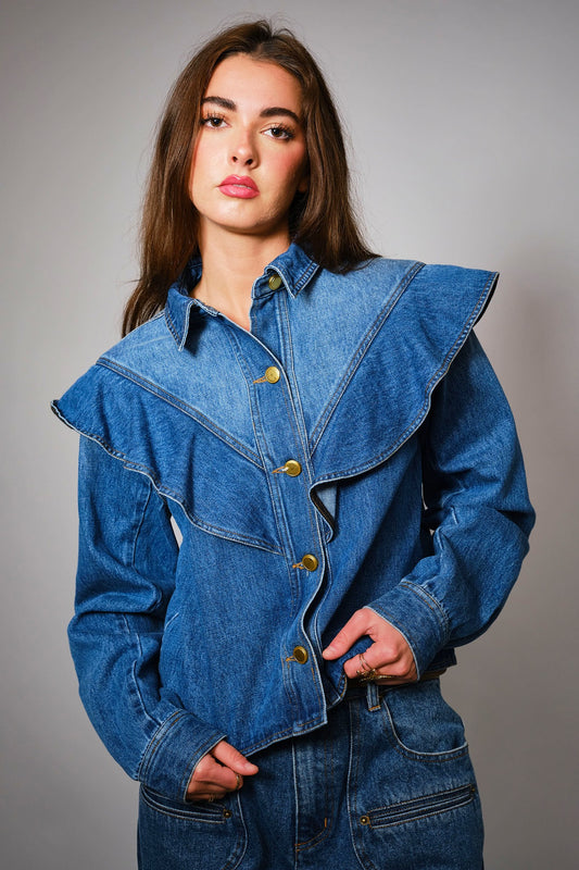 The Theodora Jacket combines contrast denim, gold buttons, and bold ruffle trim for a feminine twist on the classic jean jacket.