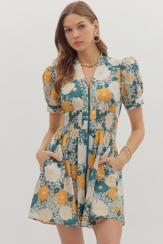 The Veda Floral Smocked Mini Dress features a romantic print, puff sleeves, and a zip-front design for easy, flattering everyday wear.

