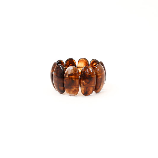 A chunky tortoiseshell stretch cuff bracelet with bold oval panels in deep brown and amber tones, perfect for adding a sophisticated yet trendy touch to any outfit.
