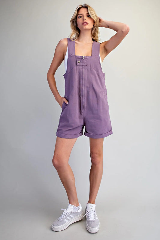 he Elspeth Utility Zip Front Romper featuring a sleeveless utility design, front zipper with snap-button tab, deep V-back, functional pockets, and cuffed hems.