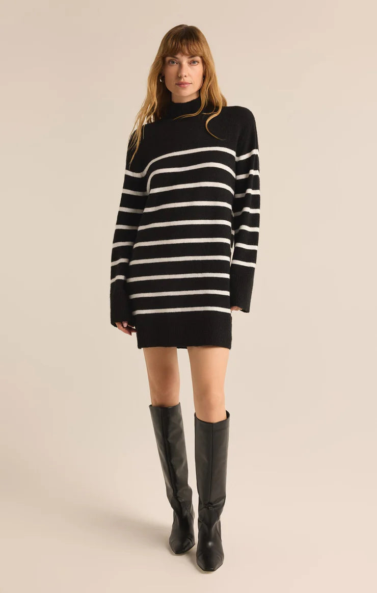 Black and white striped oversized sweater dress with a turtleneck, long sleeves, and a relaxed fit—styled with knee-high boots for a chic, modern look.