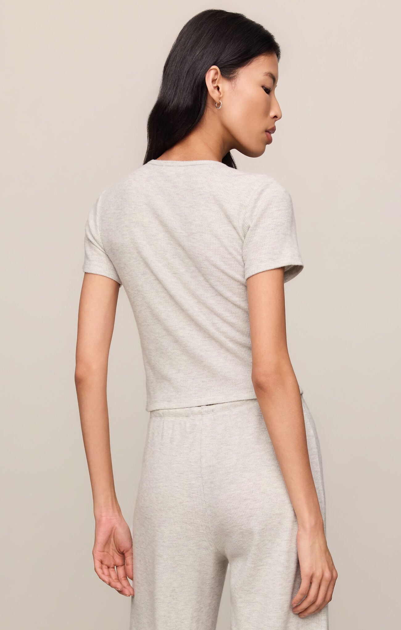 Woman wearing a light gray outfit against a plain background