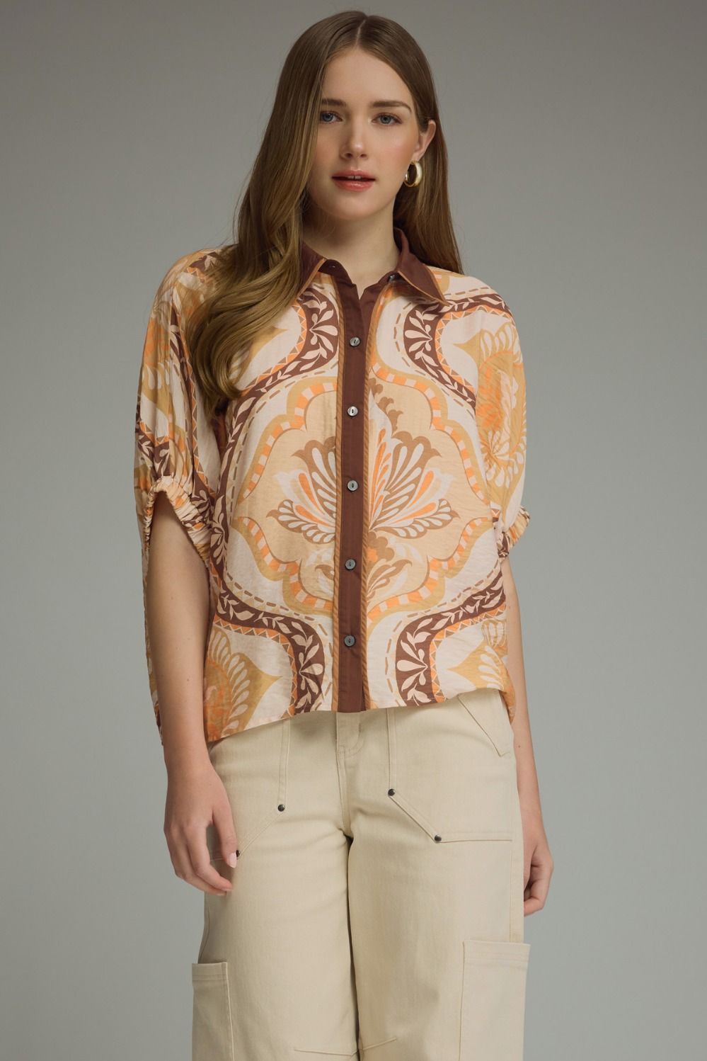 A lightweight abstract print blouse featuring relaxed dolman sleeves, contrast trim details, and an effortlessly chic silhouette.
