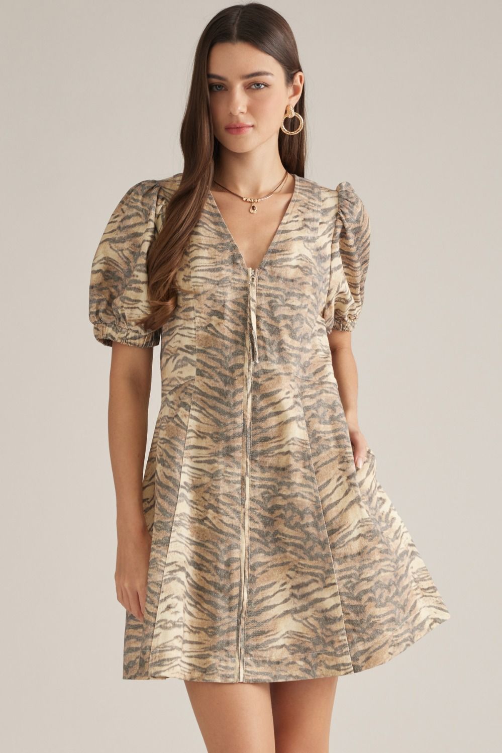 A playful cotton mini dress featuring a flattering V-neckline, short puff sleeves, and an easy front zipper closure in a chic animal print.

