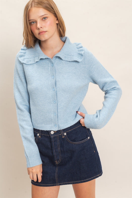 A polished knit cardigan featuring a feminine ruffled collar, classic button-front design, and ribbed cuffs for timeless everyday elegance.
